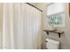 Cozy bathroom features a white shower curtain, a natural wood shelf and bright natural light from the window at 10220 E Isleta Ave, Mesa, AZ 85209