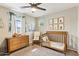 Cozy bedroom with wooden crib, dresser, decor and a ceiling fan at 10220 E Isleta Ave, Mesa, AZ 85209