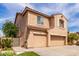 A tan two-story home featuring a three-car garage and a desert landscaped front yard at 11856 W Grant St, Avondale, AZ 85323