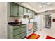 Galley-style kitchen with green cabinetry, white appliances, and tile flooring at 12943 W Maplewood Dr, Sun City West, AZ 85375