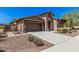 A single-Gathering home showcases desert landscaping, a front door with security gate, and a two car garage at 13641 W Jesse Red Dr, Peoria, AZ 85383