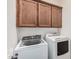 Bright laundry room equipped with a modern washer, dryer, and wood storage cabinets at 13641 W Jesse Red Dr, Peoria, AZ 85383