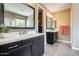 Well-lit bathroom with dual vanities, black cabinets, large mirrors, walk-in closet and a separate shower area at 15613 W Minnezona Ave, Goodyear, AZ 85395