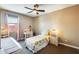 Neutral toned bedroom with two twin beds, a desk, bedside table, and a large window at 15613 W Minnezona Ave, Goodyear, AZ 85395