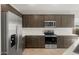 Modern kitchen featuring stainless steel appliances, dark brown cabinets, and white subway tile backsplash at 17794 W Getty Dr, Goodyear, AZ 85338
