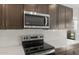 Contemporary kitchen highlights stainless steel microwave and electric cooktop above dark brown cabinetry at 17794 W Getty Dr, Goodyear, AZ 85338