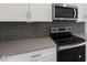 Close-up of kitchen details: grey backsplash, stainless steel stove, oven, microwave, white cabinets and light countertops at 17809 W Getty Dr, Goodyear, AZ 85338