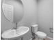 Powder room featuring a pedestal sink and a toilet, with a round mirror above the sink at 17812 W Getty Dr, Goodyear, AZ 85338
