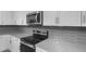 Close-up of the kitchen featuring stainless steel microwave, electric range, and modern gray backsplash at 17812 W Getty Dr, Goodyear, AZ 85338