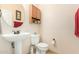 Well-lit powder room with pedestal sink, matching cabinet, toilet, and decorative accents at 2656 E Longhorn Pl, Chandler, AZ 85286