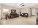 Bright living room features tile flooring, a ceiling fan, multiple windows and leather couches at 2656 E Longhorn Pl, Chandler, AZ 85286