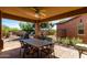 Spacious covered patio featuring a dining table, outdoor kitchen, and well-manicured landscaping at 26735 N 127Th Dr, Peoria, AZ 85383