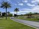 Beautifully landscaped golf course featuring a serene pond, mature palm trees and open fairway under a partly cloudy sky at 26735 N 127Th Dr, Peoria, AZ 85383