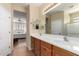 Bathroom with dual sinks, wood cabinets, and views to the main bedroom at 26735 N 127Th Dr, Peoria, AZ 85383