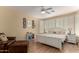 Bright main bedroom with a ceiling fan, plantation shutters, and a seating area at 26735 N 127Th Dr, Peoria, AZ 85383
