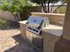 A close up image of a stainless steel outdoor grill surrounded by stone countertop with built-in drawers and storage at 26735 N 127Th Dr, Peoria, AZ 85383