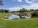 Scenic view of the community's water feature, showcasing a lush lawn, waterfall, and picturesque pond at 26735 N 127Th Dr, Peoria, AZ 85383