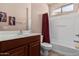 Bright bathroom featuring a tub with white surround, red shower curtain, and wood vanity at 41960 W Ellington Ln, Maricopa, AZ 85138