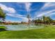 Picturesque community pond with a fountain, lush green grass, and mature trees at 540 Leisure World --, Mesa, AZ 85206