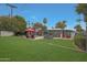 Spacious backyard with a well-manicured lawn, pool, patio furniture and stylish modern gray home at 6746 E Monterosa St, Scottsdale, AZ 85251