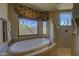 Bathroom featuring a soaking tub with jets and natural light from a window overlooking the landscape at 7373 E Clubhouse Dr # 24, Scottsdale, AZ 85266