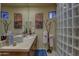 Well-lit bathroom featuring a glass block shower and dual desert landscape art pieces at 7373 E Clubhouse Dr # 24, Scottsdale, AZ 85266