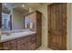Bathroom featuring a wooden vanity with white countertop, decorative mirror, and wood paneled door at 7373 E Clubhouse Dr # 24, Scottsdale, AZ 85266