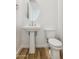 Bright half bathroom featuring a pedestal sink, oval mirror, and modern wood-look flooring at 7422 W Buckhorn Trl, Peoria, AZ 85383