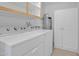 Well-lit laundry room with white washer, dryer, upper cabinet, and additional storage cabinet at 7526 E Drummer Ave, Mesa, AZ 85208