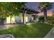 Inviting backyard with covered patio, artificial grass, and mature landscaping at dusk at 7725 N Via De Fonda --, Scottsdale, AZ 85258