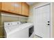 This laundry room has a white washer and dryer, white cabinets, and a door that leads outside at 7725 N Via De Fonda --, Scottsdale, AZ 85258