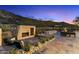 Landscaped backyard with an outdoor fireplace, desert plants, and scenic desert views at dusk at 9539 S 13Th Way, Phoenix, AZ 85042