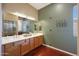 Bathroom featuring double sinks, a large mirror, beautiful hardwood floors and a glass shower door at 14442 W Lexington Ave, Goodyear, AZ 85395