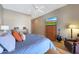 Spacious bedroom featuring light wood floors, ceiling fan, dresser, television, and an armchair at 14442 W Lexington Ave, Goodyear, AZ 85395