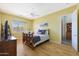 Bedroom with hardwood floors, ceiling fan, tv, and large windows looking out into the surrounding desert landscape at 14442 W Lexington Ave, Goodyear, AZ 85395