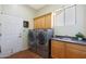 Bright laundry room featuring modern washer and dryer, storage cabinets, and a utility sink at 14442 W Lexington Ave, Goodyear, AZ 85395