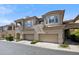 Inviting view of the townhome's facade, featuring a two-car garage, balcony, and desert landscaping in a gated community at 16420 N Thompson Peak Pkwy # 2091, Scottsdale, AZ 85260