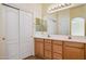 Bright bathroom with double sinks, wooden cabinets, large mirror, and convenient linen closet at 17828 N 50Th St, Scottsdale, AZ 85254