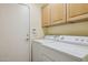 Functional laundry area with a washer, dryer, overhead cabinets, and a door at 17828 N 50Th St, Scottsdale, AZ 85254