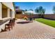 Brick backyard patio featuring green lawn, outdoor seating, and lush desert landscaping at 2185 N Beverly Pl, Buckeye, AZ 85396