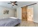 Bedroom features wood floors, barn door to the ensuite bathroom, and ceiling fan at 2185 N Beverly Pl, Buckeye, AZ 85396