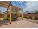 Backyard patio with stone pavers and a pergola covering a table with seating and artificial grass at 291 N Washington St, Chandler, AZ 85225