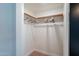 A walk-in closet features a wooden hanging rod and shelving with light-colored walls and wood-look floors at 291 N Washington St, Chandler, AZ 85225