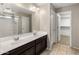 A well-lit bathroom featuring double sinks, modern fixtures, a large mirror, and access to a walk-in closet at 2929 E Binner Dr, Chandler, AZ 85225