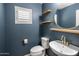 A modern powder room features a round mirror, floating shelves, and stylish fixtures against a blue painted wall at 2929 E Binner Dr, Chandler, AZ 85225