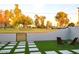 Inviting backyard featuring artificial grass, modern pavers, and a view of green space beyond the gated, white brick fence at 3041 S Country Club Way, Tempe, AZ 85282