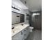 Modern bathroom featuring double sinks, stylish tile flooring, glass-enclosed shower, and industrial shelving at 332 N 25Th St, Mesa, AZ 85213