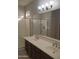 Bright bathroom features a double sink vanity, large mirror, and glass enclosed shower at 37180 W Mondragone Ln, Maricopa, AZ 85138