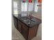 Kitchen island featuring granite countertop, stainless steel sink, gooseneck faucet, and dishwasher offering both style and practicality at 37180 W Mondragone Ln, Maricopa, AZ 85138