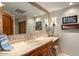 Well-lit bathroom with stone countertop, custom wood cabinetry, and decorative sconces at 42171 N Saguaro Forest Dr, Scottsdale, AZ 85262